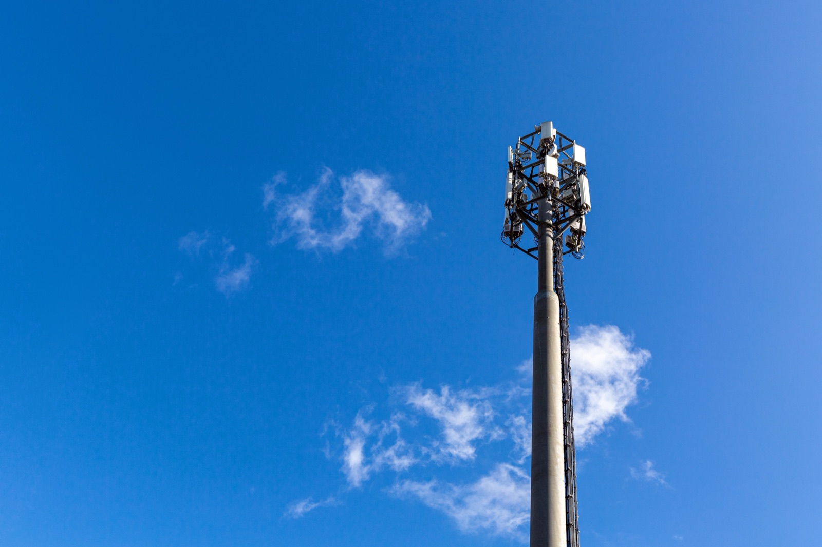 A telecommunications monopole carrying sector antennas, against open sky.